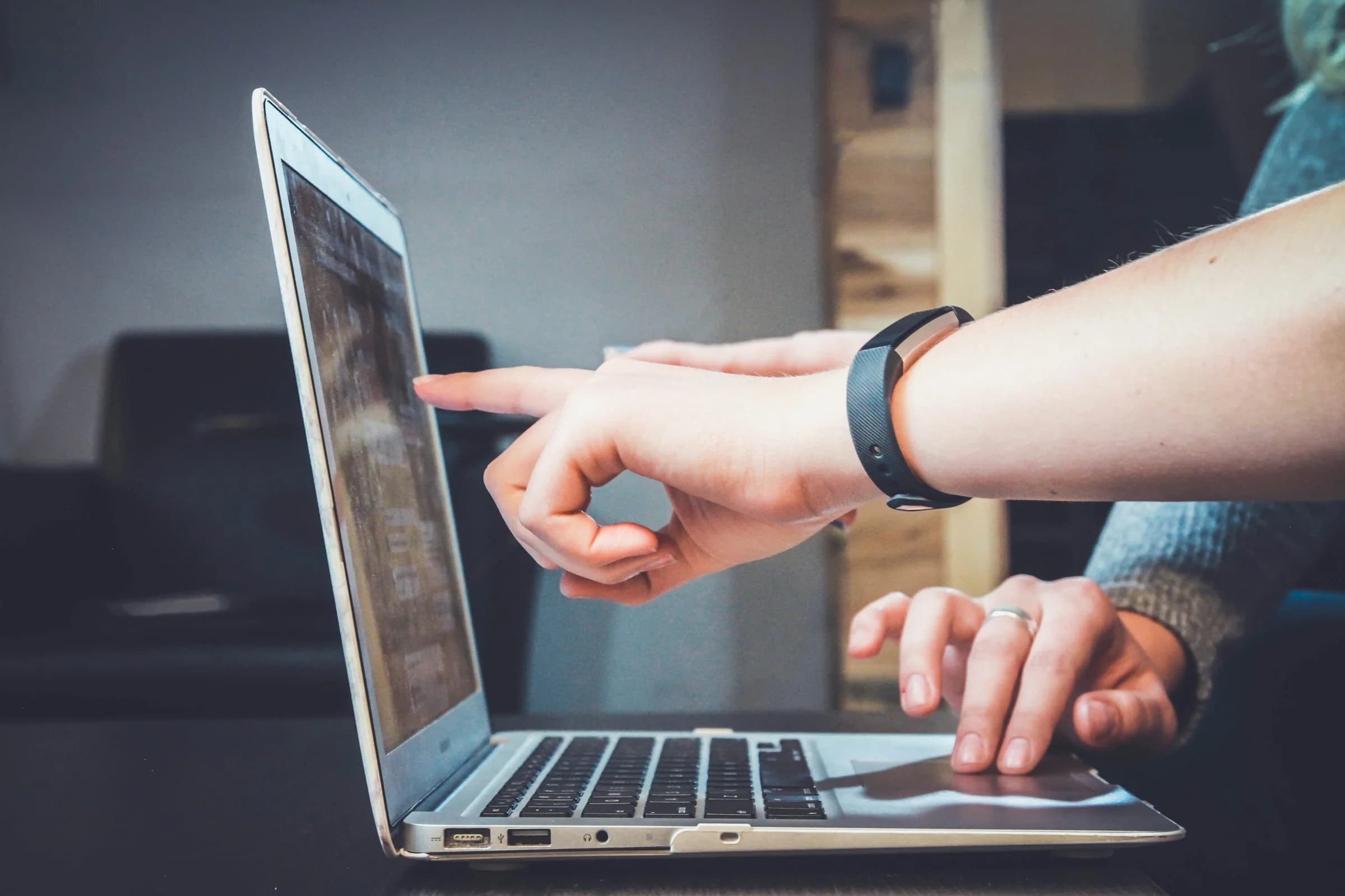 Two colleagues collaborating at a laptop, one pointing at the screen